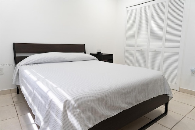 bedroom with light tile patterned floors, baseboards, and a closet