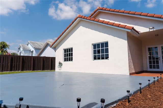 view of home's exterior with a patio area, stucco siding, french doors, and fence