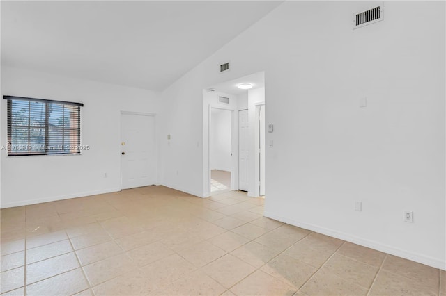 spare room with light tile patterned floors, visible vents, and lofted ceiling