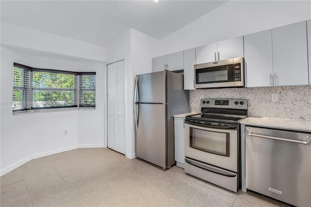 kitchen with stainless steel appliances, backsplash, light stone counters, and light tile patterned flooring