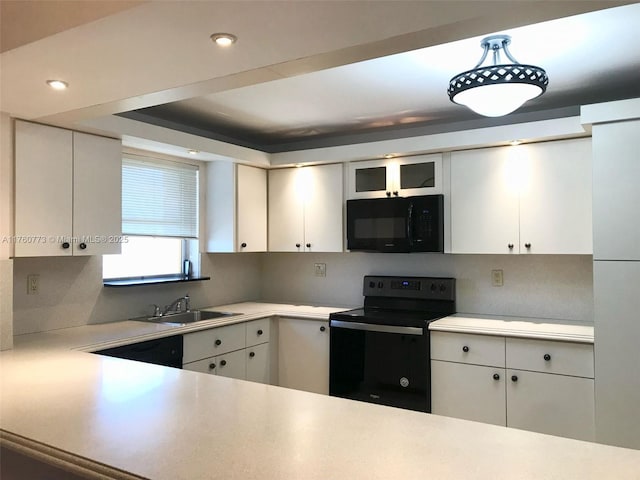 kitchen with white cabinetry, black appliances, light countertops, and a sink