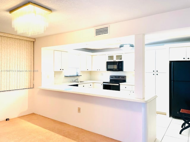 kitchen featuring visible vents, a peninsula, a sink, black appliances, and white cabinets