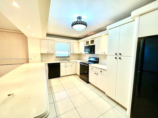 kitchen with black appliances, a sink, light tile patterned flooring, white cabinets, and light countertops