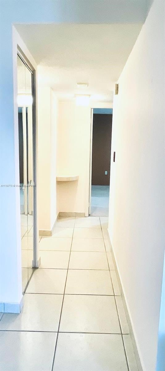 hallway featuring light tile patterned floors and baseboards