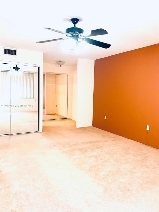 unfurnished room featuring visible vents, carpet floors, and ceiling fan