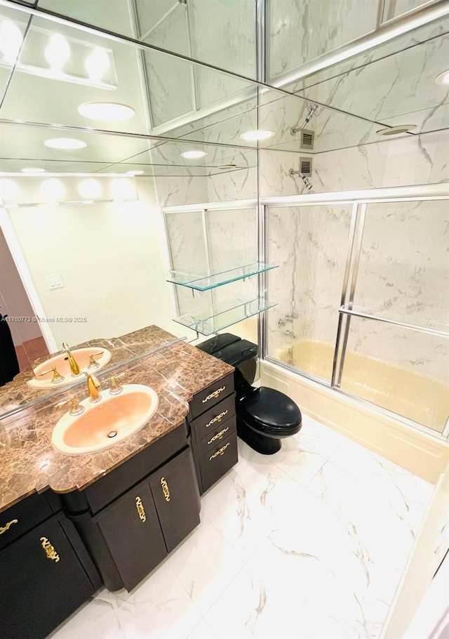 bathroom with marble finish floor, vanity, toilet, and shower / bath combination with glass door