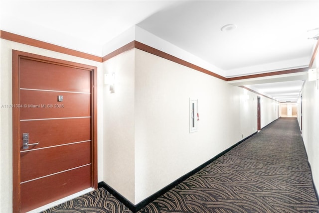 corridor featuring baseboards and dark carpet