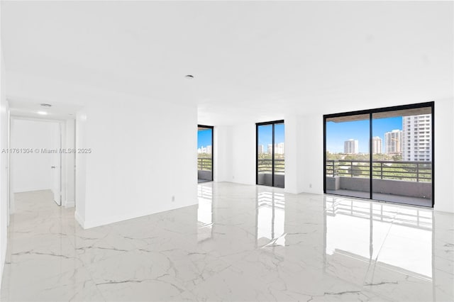 spare room with a wall of windows, baseboards, a view of city, and marble finish floor