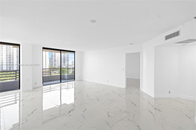 spare room with a wall of windows, a view of city, visible vents, and marble finish floor