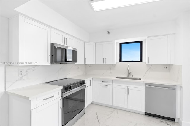 kitchen featuring backsplash, stainless steel appliances, marble finish floor, white cabinetry, and a sink