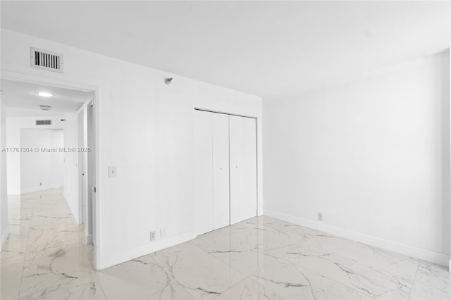 unfurnished bedroom featuring a closet, visible vents, marble finish floor, and baseboards