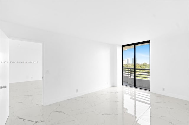 spare room with baseboards, marble finish floor, and expansive windows