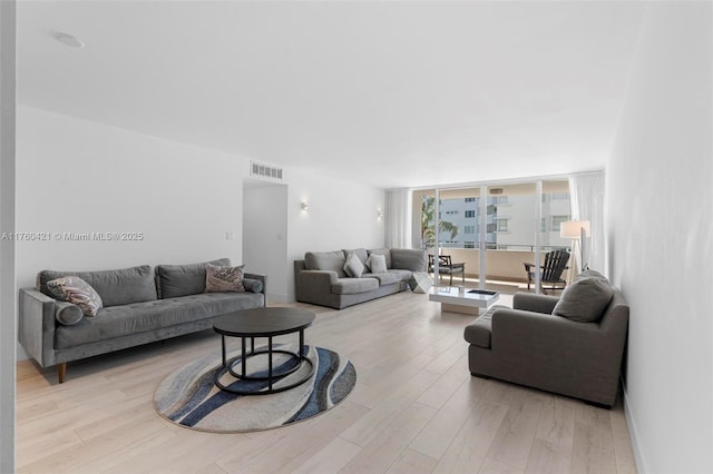 living room featuring visible vents, wood finished floors, and floor to ceiling windows