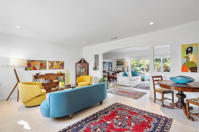 living room featuring visible vents, speckled floor, baseboards, recessed lighting, and arched walkways