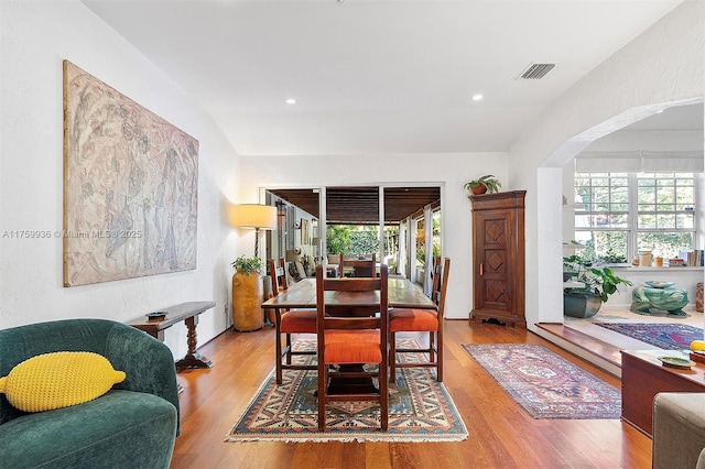 dining area featuring arched walkways, visible vents, recessed lighting, and wood finished floors