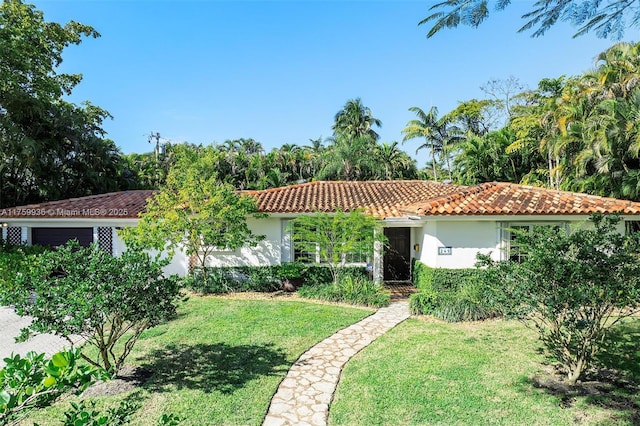 mediterranean / spanish house featuring a garage, stucco siding, a tile roof, and a front yard
