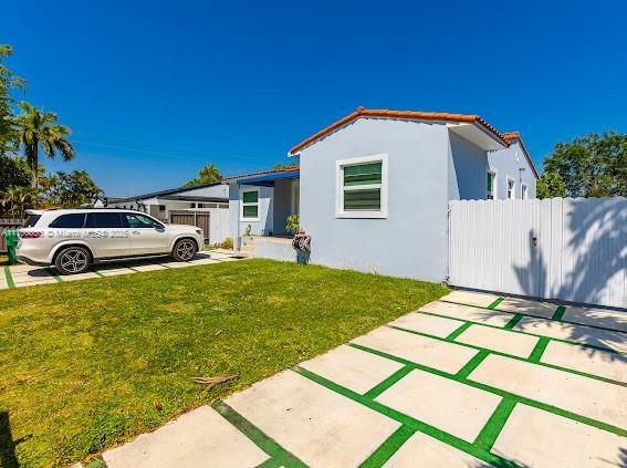 exterior space with a yard, fence, and stucco siding