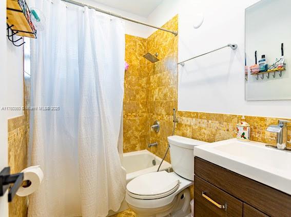 bathroom with vanity, tile walls, toilet, and shower / bath combo