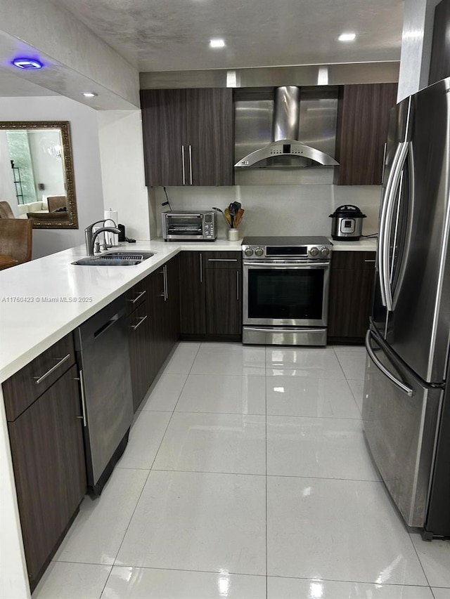 kitchen with modern cabinets, a sink, wall chimney range hood, stainless steel appliances, and light countertops