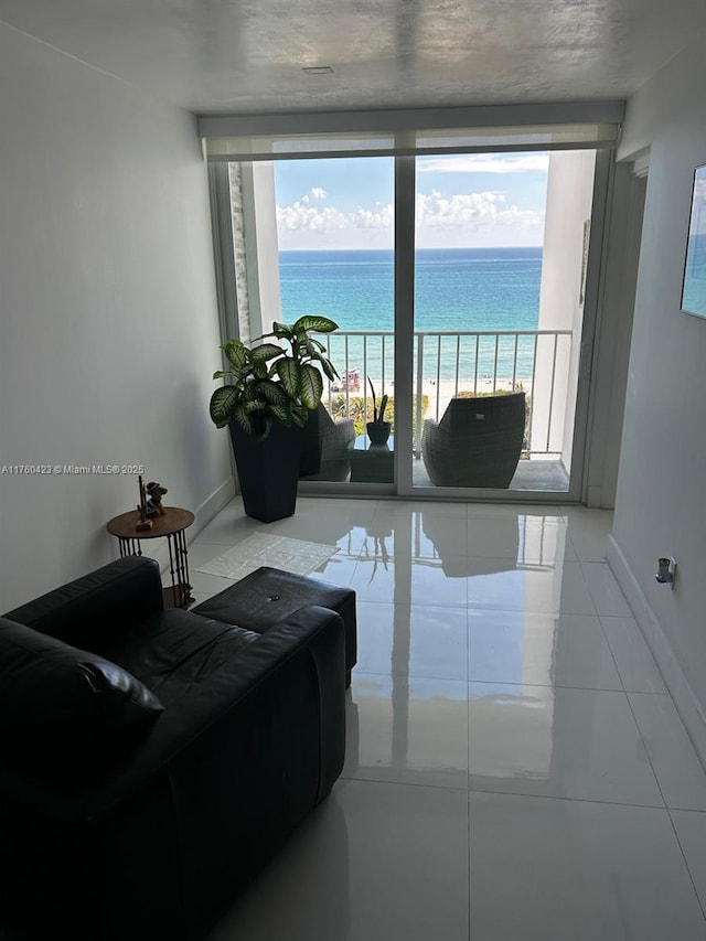 tiled living room featuring plenty of natural light, baseboards, and a water view