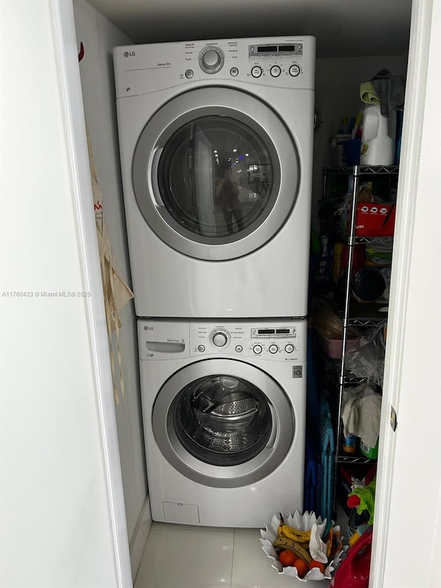 clothes washing area with laundry area, stacked washer / dryer, and tile patterned floors