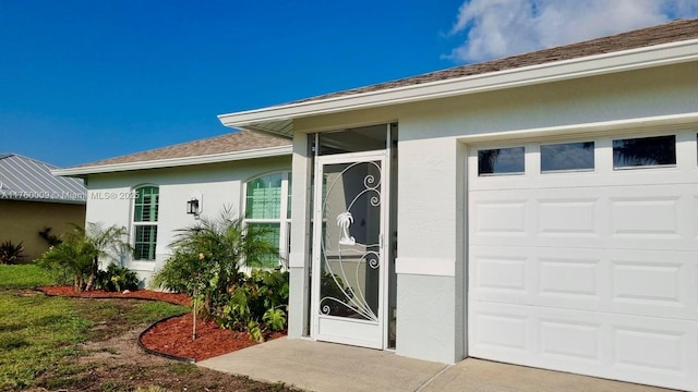 property entrance featuring a garage, roof with shingles, and stucco siding