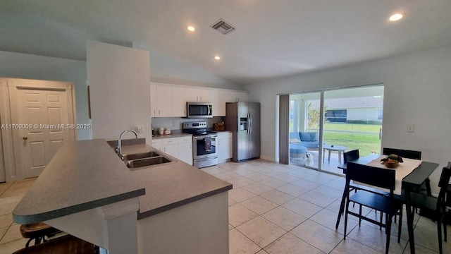 kitchen featuring visible vents, a sink, a kitchen breakfast bar, white cabinetry, and stainless steel appliances