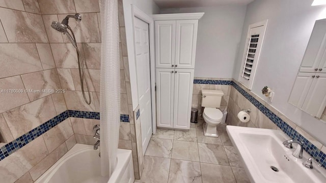 bathroom featuring tile walls, shower / tub combo, toilet, and wainscoting