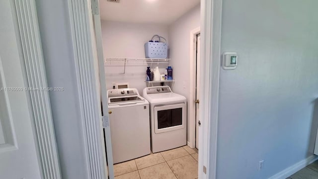 laundry room featuring light tile patterned flooring, laundry area, and washing machine and clothes dryer