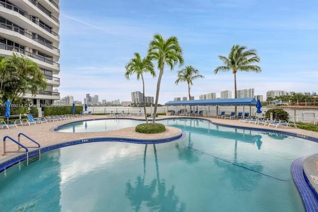 pool with a patio area, a city view, and fence