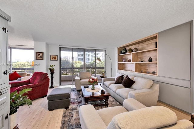 living room featuring a wall of windows, light wood-style flooring, a textured ceiling, and a wealth of natural light