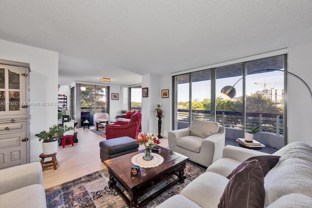 living room with expansive windows, plenty of natural light, a textured ceiling, and wood finished floors