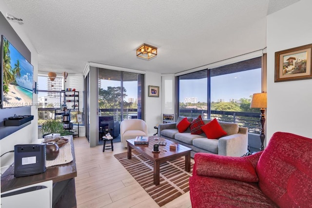 living room featuring floor to ceiling windows, a textured ceiling, and light wood-style flooring