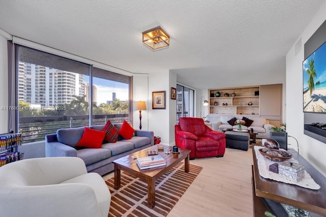 living room featuring a wall of windows, wood finished floors, and a textured ceiling