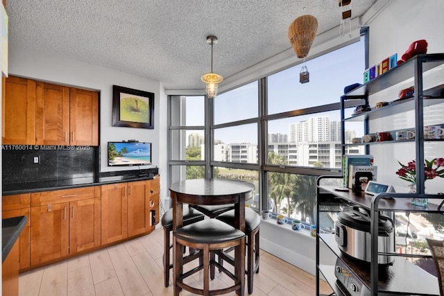 dining area with light wood-style flooring, a textured ceiling, and baseboards