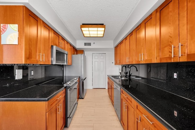 kitchen with a sink, backsplash, appliances with stainless steel finishes, and brown cabinetry