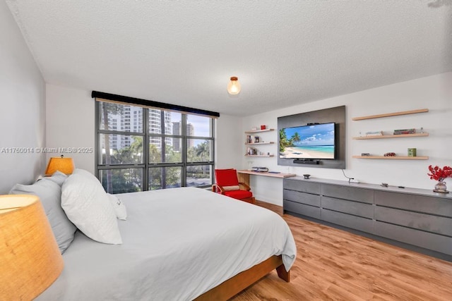 bedroom with a textured ceiling and light wood-style floors