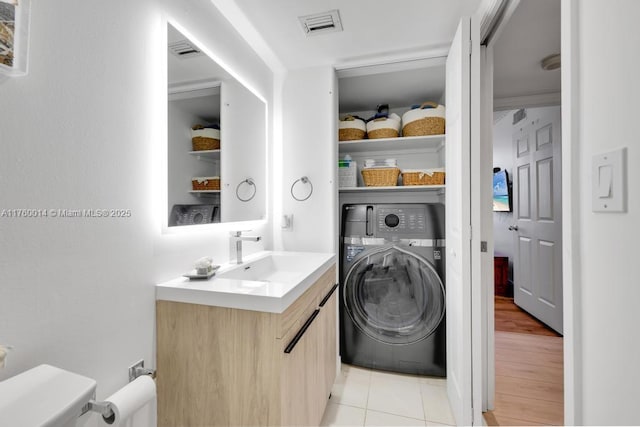 laundry area featuring visible vents, a sink, washer / clothes dryer, light tile patterned floors, and laundry area