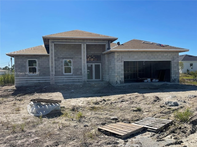 back of house featuring french doors, roof with shingles, and an attached garage