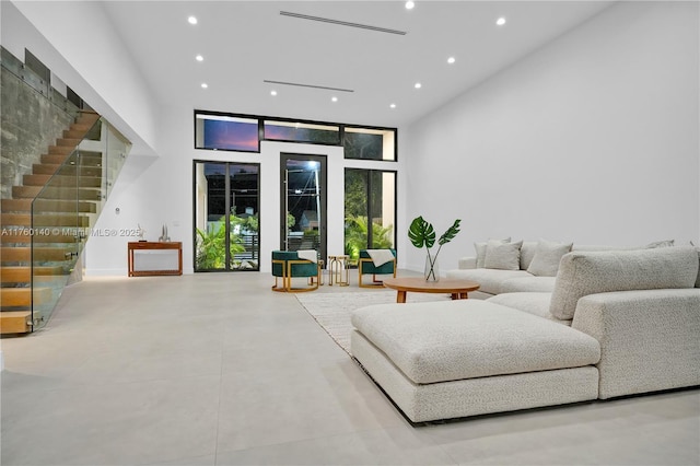 living room featuring stairway, recessed lighting, and a towering ceiling