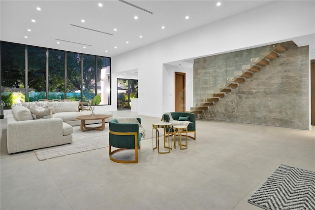 living area with recessed lighting, stairway, a high ceiling, and concrete flooring