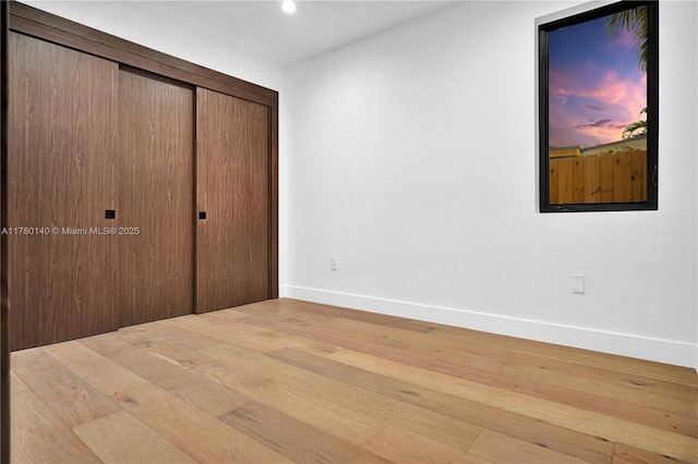 unfurnished bedroom featuring a closet, baseboards, and wood finished floors
