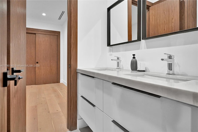 full bath featuring a sink, visible vents, hardwood / wood-style floors, and double vanity