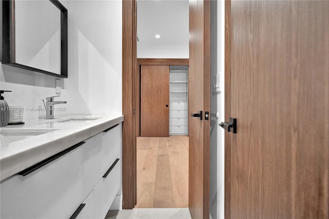 hall featuring a sink, light wood-type flooring, and recessed lighting