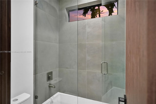 bathroom featuring toilet and a shower with door