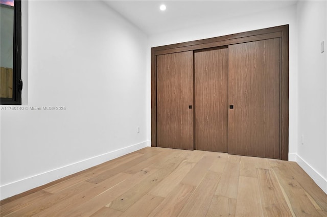 unfurnished bedroom featuring recessed lighting, a closet, baseboards, and hardwood / wood-style flooring