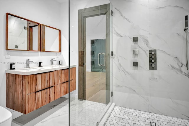 bathroom with a marble finish shower, double vanity, toilet, and a sink