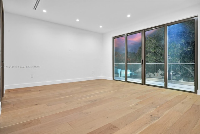 empty room featuring recessed lighting, baseboards, floor to ceiling windows, and light wood finished floors
