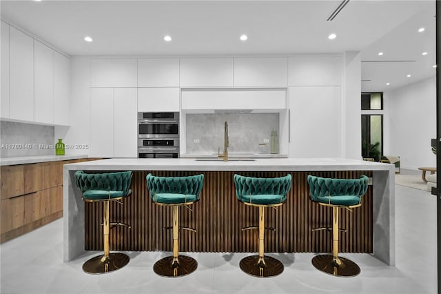 bar with decorative backsplash, recessed lighting, double oven, and a sink