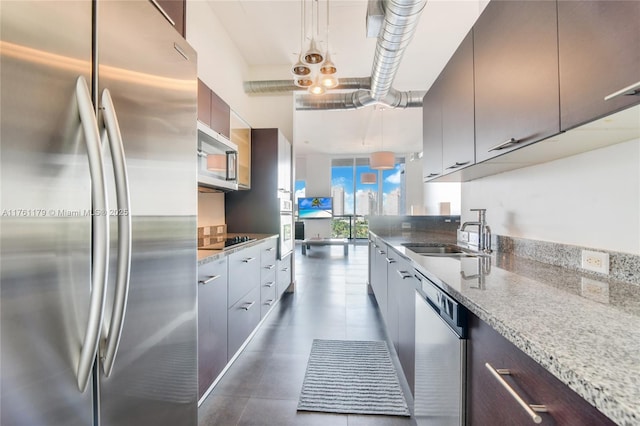 kitchen featuring light stone counters, stainless steel appliances, modern cabinets, and a sink